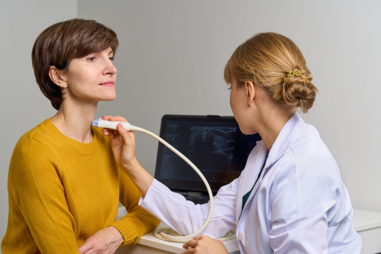 Untersuchung einer Patientin am Hals mit modernen Geräten für die Ultraschalldiagnostik.